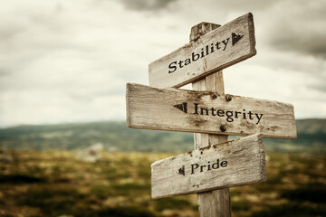 stability integrity pride text quote written in wooden signpost outdoors in nature. Moody theme feeling.