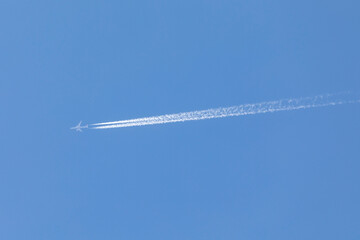 aviation, travel by airplane, airplane flying on a sunny day, sky without clouds, and leaves a large jet stream behind