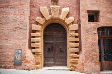 Ancient medieval wooden door with decorations in the city of Siena, Italy
