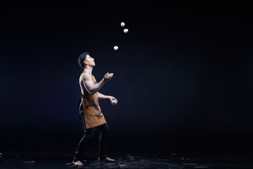 Fototapeta na wymiar A man profession juggler, is juggling a balls isolated on black background