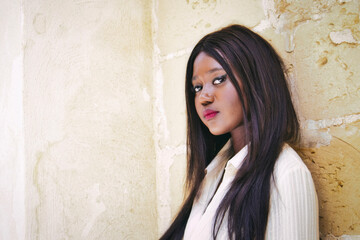 Beautiful black African woman model posing against a wall looking directly at the camera