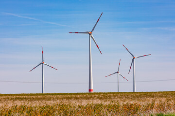 Windräder dominieren eine ländliche Landschaft vor blauem Himmel in Deutschland