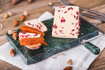 Delicious British Cheddar cheese with cranberry on a marble cheese cutting table.