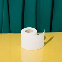Minimal creative concept made of toilet paper on a glass yellow table and an elegant green curtain.