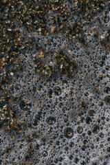 top view of a foamy sea wave breaking on a summer pebble beach