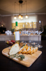 cut baked bread with herbs, against a background of wine and glasses.