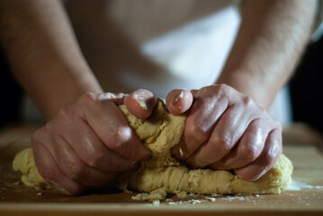 Baker's hands working the flour dough on a wooden board