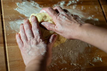 Fototapeta premium Baker's hands working the flour dough on a wooden board