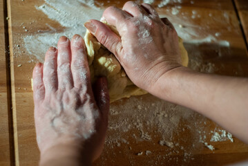 Fototapeta premium Baker's hands working the flour dough on a wooden board