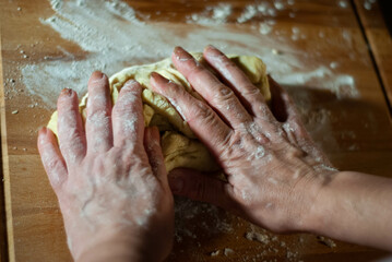 Fototapeta premium Baker's hands working the flour dough on a wooden board