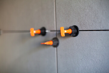 Tile leveling system with plastic clips.Tile leveling system. Tiler installing large format tile on wall. tile leveling system