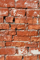 Texture of a red brick wall with remnants of cement and white paint, rough brickwork, vertical format