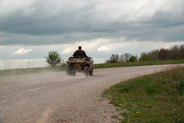 a farmer quad biker throws up clouds of dust riding his off-road quad bike along a stone track open countryside © Martin