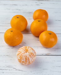Tangerines with cut fruit over wooden table