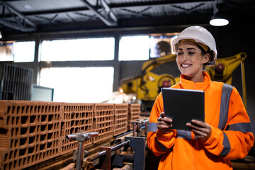 Production line female worker holding tablet computer and checking quality of the process in manufacturing factory.