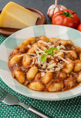 Italian pasta gnocchi on a plate with bolognese sauce, basil and parmesan cheese