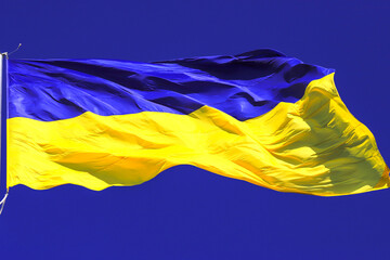 Flag of Ukraine flutters in blue sky. Large yellow blue Ukrainian national state flag, city Kyiv Ukraine. Symbol of Ukraine victory in war against Russian aggression