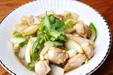 Stir-fried pork with chilli with onions and spring onions served in a white plate, Stir-fried pork with chilli is a popular Thai dish that Thai people eat.