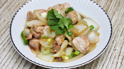Stir-fried pork with chilli with onions and spring onions served in a white plate, Stir-fried pork with chilli is a popular Thai dish that Thai people eat.