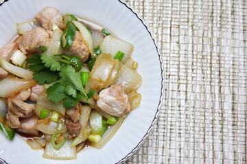 Stir-fried pork with chilli with onions and spring onions served in a white plate, Stir-fried pork with chilli is a popular Thai dish that Thai people eat.