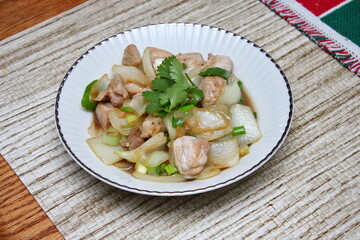 Stir-fried pork with chilli with onions and spring onions served in a white plate, Stir-fried pork with chilli is a popular Thai dish that Thai people eat.