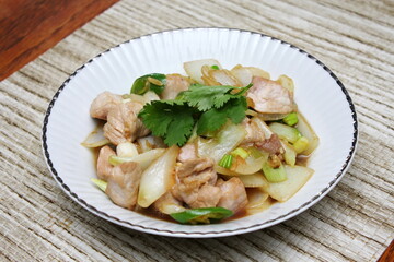 Stir-fried pork with chilli with onions and spring onions served in a white plate, Stir-fried pork with chilli is a popular Thai dish that Thai people eat.