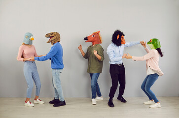 Happy eccentric young people with heads of various animals dance and have fun together. Five casual...