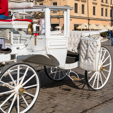 Close-up of a white carriage with big wheels on the stone pavement of the old city on a sunny day. Tourist travels in Europe, romantic city tours on vintage transport
