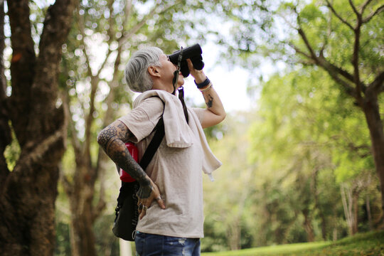 senior woman using binoculars to spot animals and things while hiking with backpacks and trekking in the forest. Concept of active lifestyle on retirement..