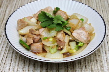 Stir-fried pork with chilli with onions and spring onions served in a white plate, Stir-fried pork with chilli is a popular Thai dish that Thai people eat.