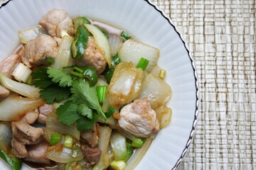 Stir-fried pork with chilli with onions and spring onions served in a white plate, Stir-fried pork with chilli is a popular Thai dish that Thai people eat.