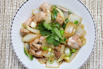 Stir-fried pork with chilli with onions and spring onions served in a white plate, Stir-fried pork with chilli is a popular Thai dish that Thai people eat.