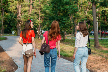 Group of girl friends jumping outdoors on sunset city public park. Young multi-ethnic hipster friends dancing at summer park. Group of women friends hugging and ejoying the sunset in outdoor nature