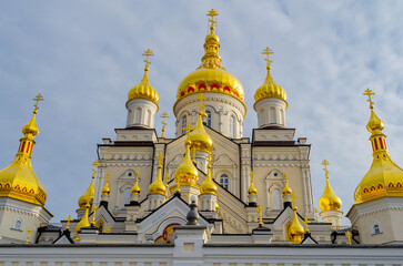 Golden domes with crosses of the Orthodox Christian religious building against the cloudy sky....
