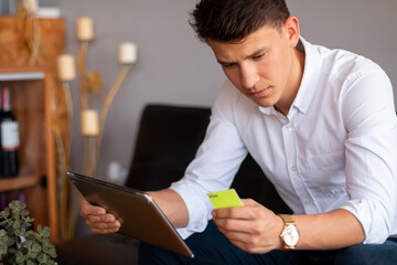 Fototapeta premium Businessman making electronic transactions with a tablet and his visa card. Handsome and elegant young man using internet and technology.