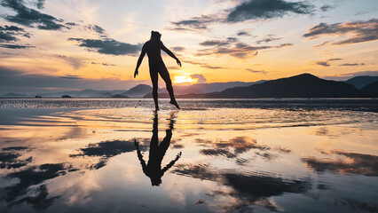 Silhueta de um homem se exercitando na beira da praia durante pôr do sol