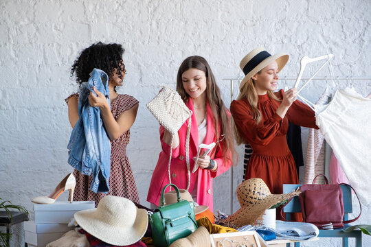 Young women choose things at flea market. Casual clothes, shoes, hats, bags, jewellery. Idea of exchange your old wardrobe for new. Eco friendly cloth concept. Zero waste shopping, reduce and reuse