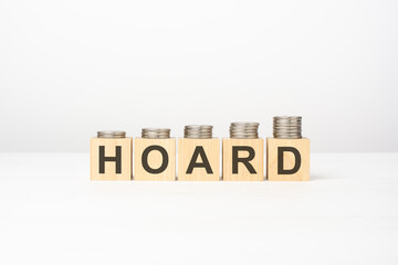 Obraz premium HOARD text written on wooden block with stacked coins on white background