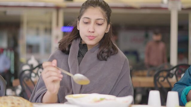 A young woman drinks tarhana soup at restaurant, a traditional Turkish dry soup, from a porcelain bowl with a spoon. Healthy and delicious dish. It is drinking for healing even when sick.