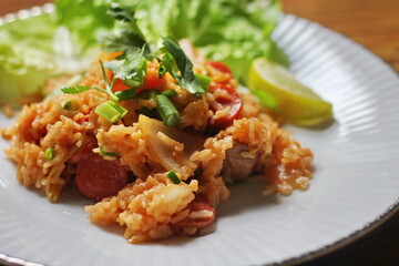 Pork and sausage fried rice served in a plate with lettuce and coriander garnish. Fried rice is a street food that is sold in Thailand.