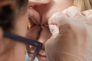 Nose Bridge Piercing Professional holding the jewel of piercing day just before screw the ball.