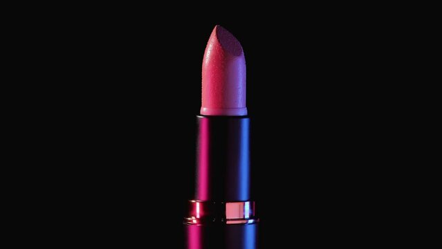 A tube of women's lipstick rotates counterclockwise on a black background. Black plastic case with gold ring and pink retractable lipstick. Close-up shooting.