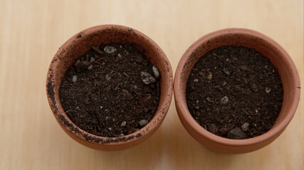 Two small terracotta pots sit filled with potting mix