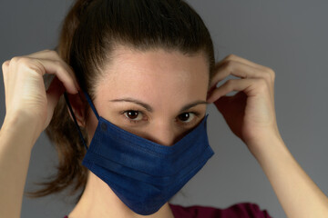 nurse in purple uniform looking at camera while putting on surgical mask