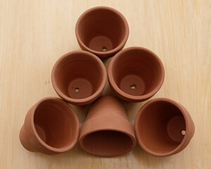 Six brown terracotta pots are waiting to be potted up, they show their drainage holes.