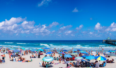 umbrellas on beach with people relaxing. tourist visiting Florida. clouds in sky over sea 