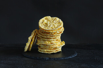 Pyramid of round corn tortillas, side view. Corn biscuits on a black shabby background