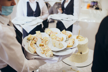 waiter in a restaurant at a banquet with plates and food on a tray