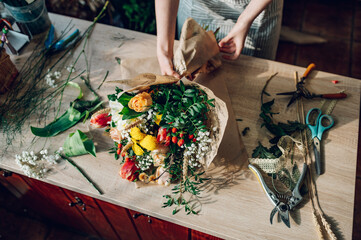 Woman florist hands making a bouquet while working in a flower shop
