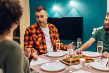 Group of friends enjoying dinner while sitting at the kitchen table together